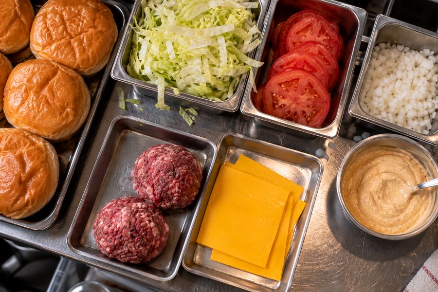Panes, carne, cheddar, lechuga, tomate, cebolla y salsa listos para armar
